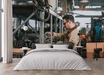 side view of manual worker looking for parts at warehouse of metal manufacturing plant. Wall mural