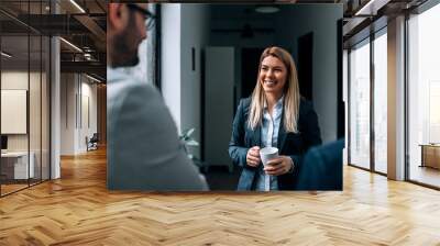 Smiling blonde business woman drinking a cup of coffee with her collegues. Wall mural