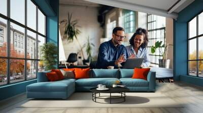 Smiling businessman showing a new project to his female colleague. Wall mural