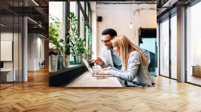 Smiling couple looking at laptop screen indoors. Discussing the good news. Wall mural