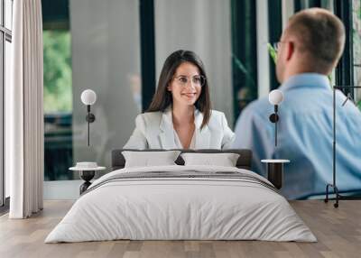 Smiling young corporate personnel manager talking to a male job applicant. Wall mural