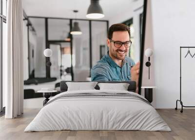 Smiling young man writing on a flipchart. Wall mural