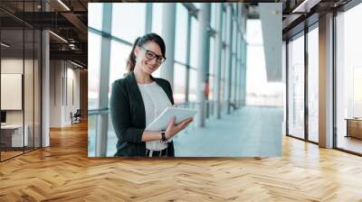 Successful and satisfied businesswoman, holding a notebook,looking at camera. Wall mural