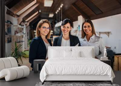 three female colleagues at a work meeting smiling to camera. Wall mural