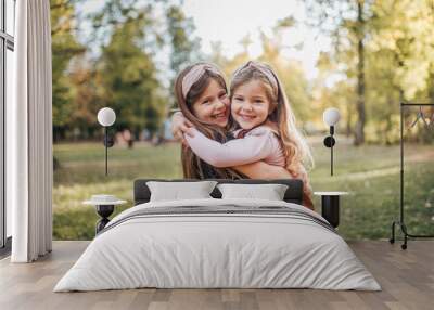 Two beautiful child sisters hugging in the park on a sunny day, portrait. Wall mural