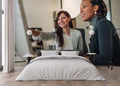 Two beautiful women working together in the office. Wall mural