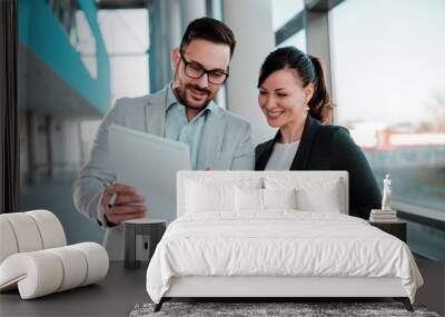 two business people discussing over documents in office lobby near window. Wall mural