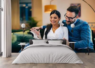 Two colleagues in love reading a book, smiling during the work break at the office. Wall mural