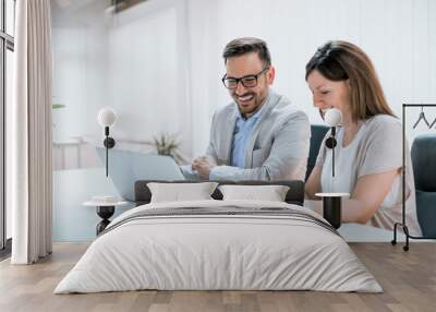 Two entrepreneurs sitting together working in an office Wall mural