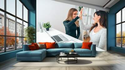 Two young business women giving high-five in modern office. Celebrating success. Wall mural