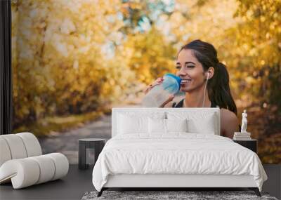 woman athlete takes a break, drinking water. Wall mural