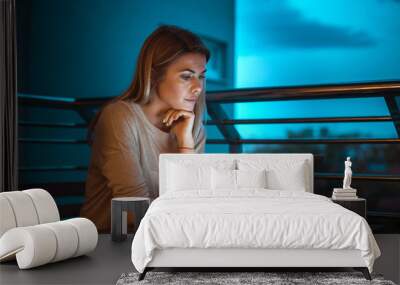 Young beautiful blonde woman working on laptop at night. High ISO image. Wall mural