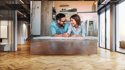 Young couple lying on a floor at home. Wall mural