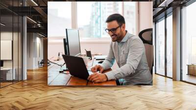 Young entrepreneur freelancer using a laptop in coworking space. Wall mural