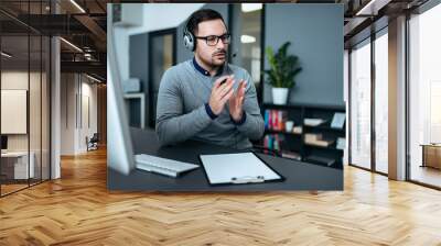 Young handsome male customer support phone operator with headset working in his office. Wall mural