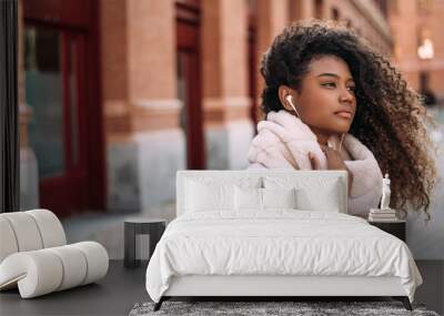 Young woman enjoying listening music outside in city. Wall mural