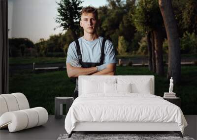 A young male gardener in overalls uses a lawn mower. Wall mural