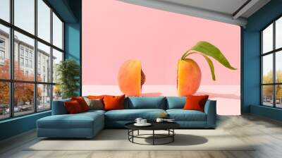 Fresh ripe organic peach with pit and leaves cut in half against bright peach pink background. Minimal fruit concept. Healthy juicy food trendy composition. Wall mural