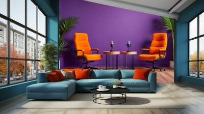 A modern podcast studio setup with two orange chairs, microphones on small round tables, potted plants, and a purple accent wall in the background, perfect for content creation or interviews.
 Wall mural