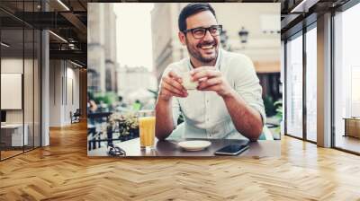 Young man sitting in the cafe and drinking coffee. Lifestyle concept Wall mural