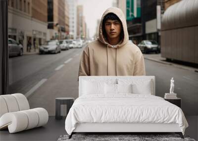 a young man wearing a blank beige hooded sweatshirt with kangaroo pockets on a city street Wall mural