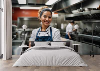 Smiling female chef with arms crossed against the backdrop of a restaurant kitchen Wall mural