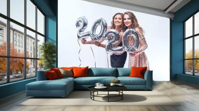 Happy young women in dresses with metallic foil 2020 balloons on white background. Wall mural