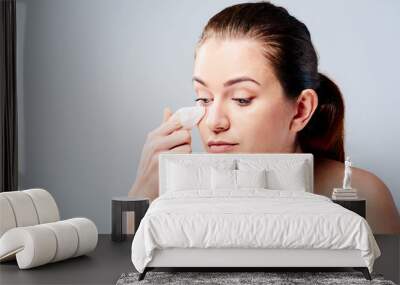 Portrait of a young woman who cleans her face with wet wipes Wall mural