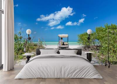 Young man driving on a golf cart at tropical white sandy beach Wall mural