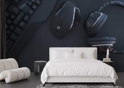 Black mouse, the keyboard, the headphones are isolated on a dark background, the top view. Flat lay gamer background. Workplace with a keyboard, mouse and headphones on a black background. Copyspace Wall mural