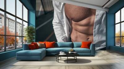 Close-up. The relief body of an athletic man. Outdoors. Green colors. Sports ground. Wall mural