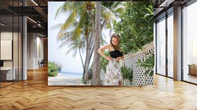 photo of good looking woman on on vacation   in summer dress on the beach with palm trees  and ocean background Wall mural