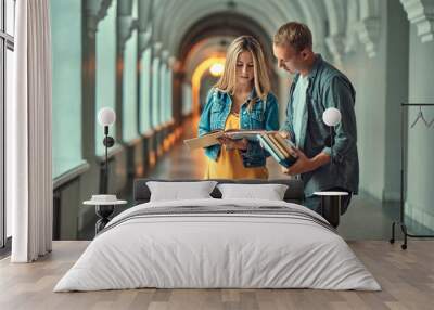 The guy and the girl are looking at the book. Wall mural