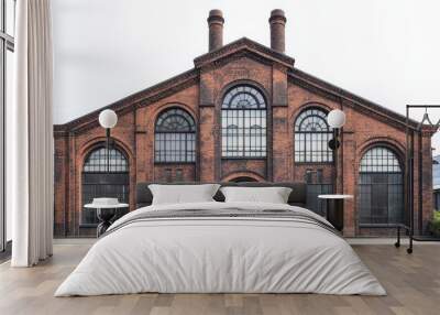 A large brick industrial building with arched windows and a symmetrical facade. Wall mural