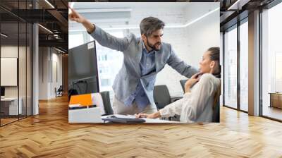 Angry boss firing upset female employee in office. Young male business manager yelling at scared and stressed business woman at her workplace. Wall mural