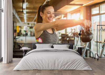 Beautiful young fit woman exercising with kettle bell at gym Wall mural