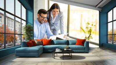 Business man and woman sitting in front of laptop and working together on a project, discussing business strategy that aims to produce results for a company. Panoramic view, copy space. Wall mural