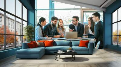 Business professionals using laptop for research and teamwork in a modern office, focusing on connection and collaboration. Wall mural