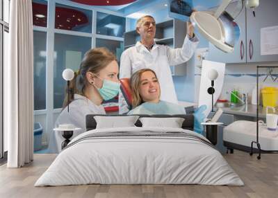 Female nurse explaining dental report to patient with dentist in the background. Wall mural