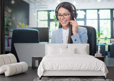 Friendly female customer support operator using laptop in office Wall mural