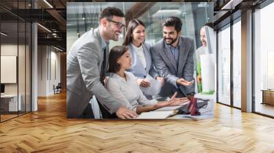 Group of happy cheerful businesspeople working around computer during meeting in modern office. Wall mural