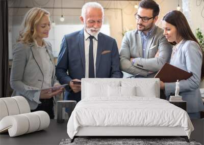 Group of multi-aged business people analyzing paper documents together in office Wall mural