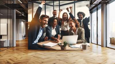 Happy diverse successful business team celebrating a triumph with arms up in startup office. Multiethnic business group with laptop screaming and holding fists up. Wall mural