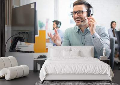 Happy handsome technical support operator with headset working in call centre Wall mural