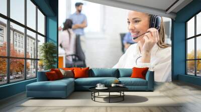 Portrait of beautiful young female customer support agent with headset working in call center Wall mural