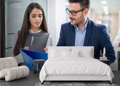 Portrait of two business people commenting some paper documents while walking through office hall. Wall mural