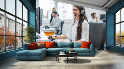 Portrait of young attractive happy smiling female customer support phone operator at modern office Wall mural