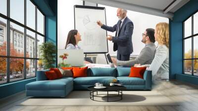 Senior businessman giving a flipchart presentation to his business colleagues in boardroom. Wall mural