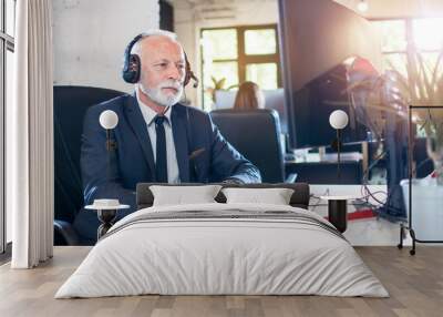 Senior businessman in headset working on computer in office Wall mural