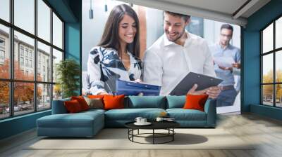 Smiling business team behind glass wall in office looking at folder. Wall mural